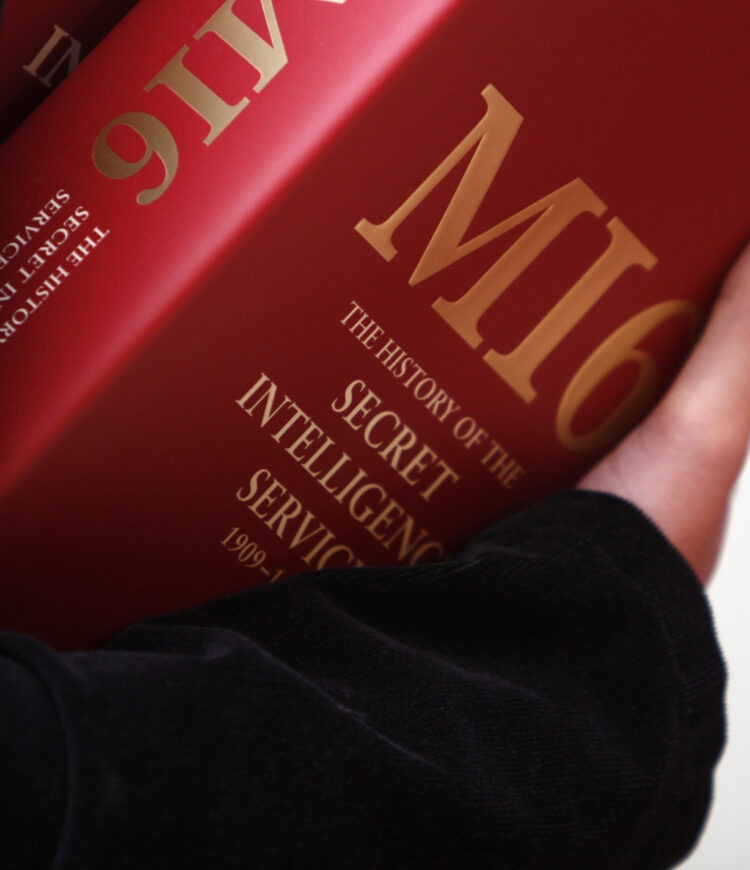Closeup of an arm holding a copy of "MI6: The History of the Secret Intelligence Service 1909-1949"